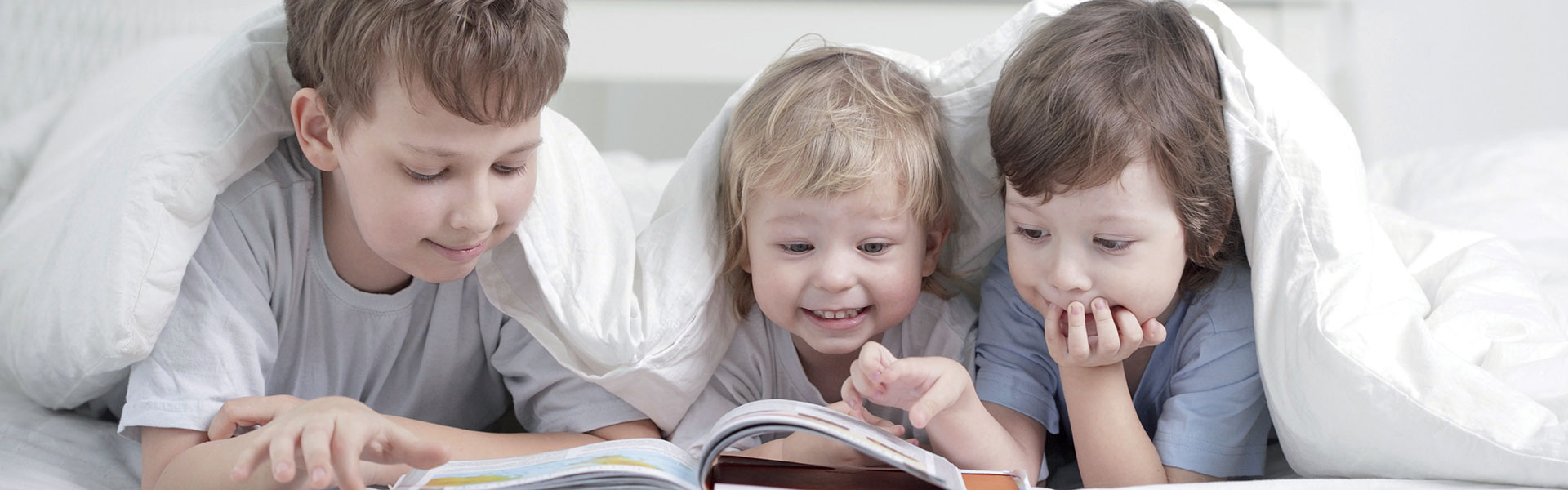 Children reading a book under duvet - GForce New Zealand